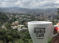 Una taza donde aparece escrito Caracas quiere cafè y en el fondo la imagen de la ciudad de Caracas