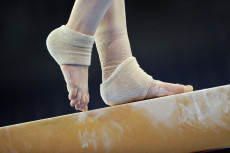 I piedi di una ginnasta sulla trave d'equilibrio.
