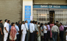 Correntisti in fila fuori da una sede della banca in India.