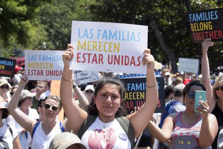 Una delle donne nella manifestazione con un cartello con la scritta "Las familias merecen estar unidas"