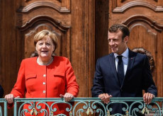 Angela Merkel e Emmanuel Macron posano per la foto ricordo, affacciati al balcone.