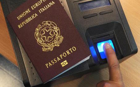 Un dito si appoggia sull'apparecchiatura per raccogliere le impronte digitali e un passaporto italiano