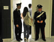 Una persona entra nella caserma dei carabinieri con due piantoni a lato