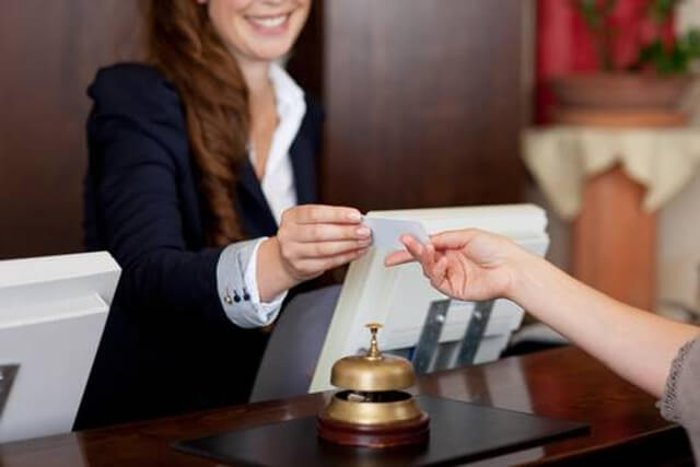 Una impiegata della recepcion di un albergo riceve il pagamento di un cliente
