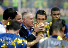 Didier Deschamps bacia la Coppa circondato dai suoi giocatori.