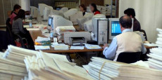 Un ufficio pubblico: scartoffie sui tavoli e impiegati statali lavorando col computer