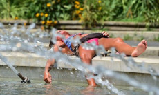 Persona distesa sul dorso di una fontana pubblica , schizzi d'acqua.