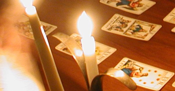 Carte da cartomante su un tavolo illuminato da due candele.