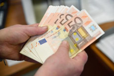 Alcune banconote da 50 Euro in mano a un cassiere di una banca.