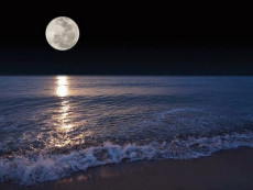Luna piena in lontananza si riflette sul mare