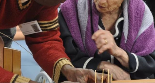 Le mani di un migrante aiutano un'anziana.