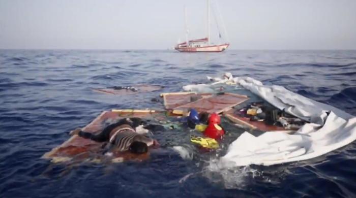 Migranti in mare aggrappati a tavole galleggianti.