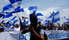 Una manifestazione di oppositori di Ortega , in prima fila un uomo con cappuccio nero imbracciando un mortaio.