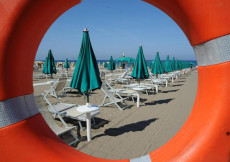Una spiaggia con sdraie e ombrelloni chiusi
