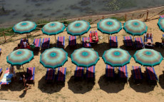 La spiaggia sul Tevere: una serie di ombrelloni sulla spiaggia lungotevere visti dall'alto.