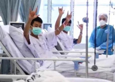 foto ospedale, alcuni ragazzi grotta gia in piedi e salutando con le braccia alzate e la mascherina sul viso
