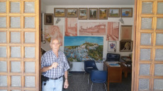 Il modenese Carlo Banchieri Righi sulla porta del suo atelier, sullo sfondo alcuni suoi quadri.