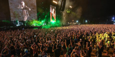 Folla assiepata in un concerto di Vasco Rossi, schermi giganti con la sua immagine.