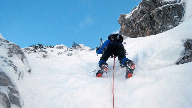 Alpinista in cordata sulla neve della montagna