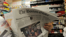 Una persona seduta in poltrona leggendo il Boston Globe