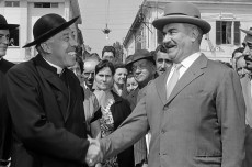 Don Camillo e Peppone si stringono la mano sorridendo.