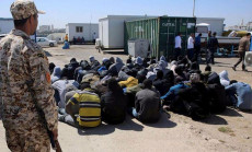 Un campo di rifugiati in Libia guardati a vista da un soldato.