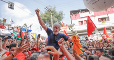 Lula portato a spalla dai suoi sostenitori con bandiere rosse.