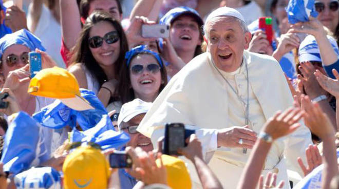 Papa Francesco circondato da un gruppo di giovani festanti.