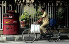 Un postino indiano consegna la corrispondenza in bicicletta.
