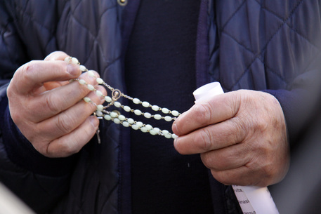 Due mani reggono un rosario