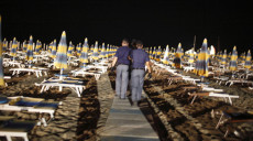 Spiaggia di sera e poliziotti camminando sulla passerella verso la riva