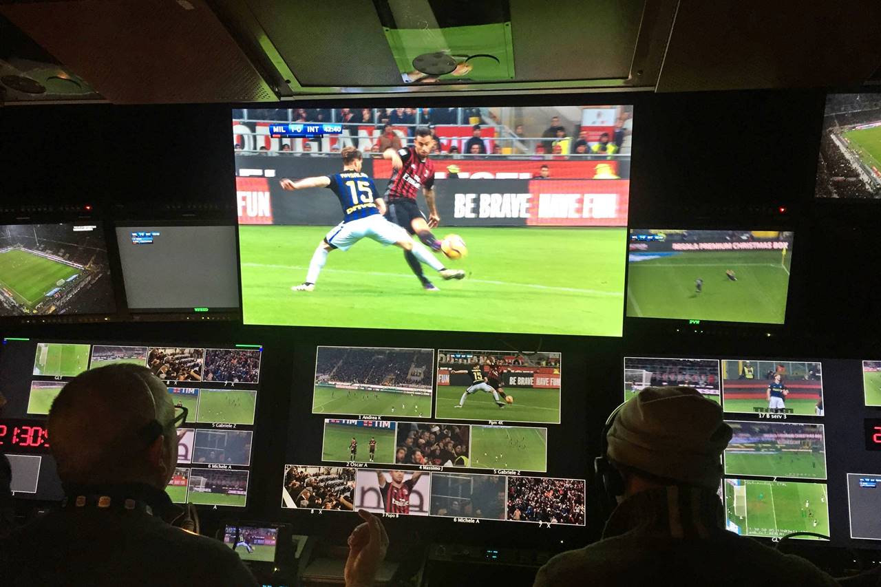 Immagini di una partita di calcio su uno schermo gigante in un negozio e due spettatori