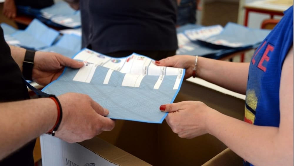 Elezioni Regionali: una persona riceve il modulo per votare.