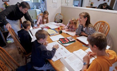 Homeschooling: Due genitori con i bambini, libri e quaderni sul tavolo