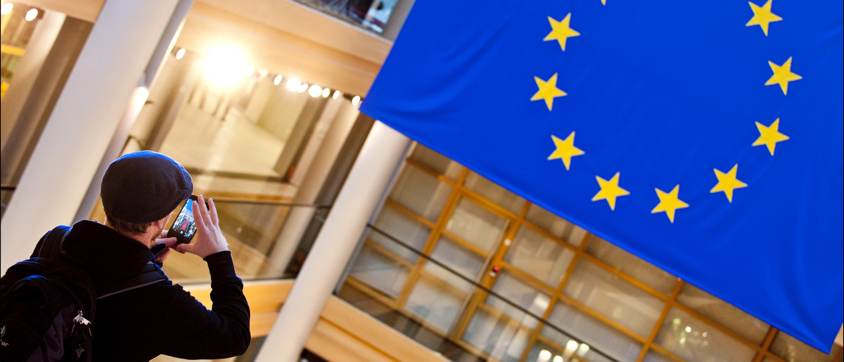 Un ragazzo col cellulare fotografa la bandiera europea.