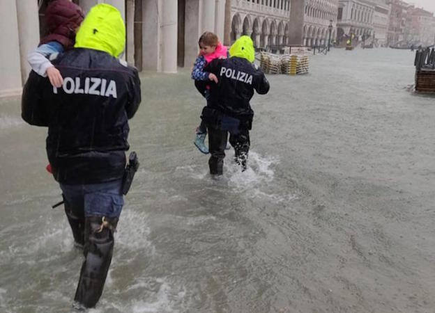 Maltempo: Una foto tratta dal profilo Twitter della Polizia di Stato che ritrae il momento in cui due agenti mettono in salvo due turisti bloccati dalla marea in Piazza San Marco, Venezia.