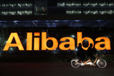 In bicicletta su un tandem di fronte alla scritta pubblicitaria Alibaba di notte