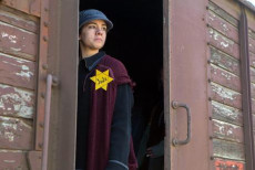 Una ragazza con la stella gialla sul vestito, fotografata sulla porta di un vagone di treno. Ebrei