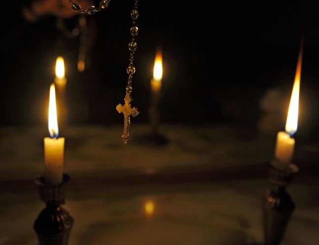 Un crocifisso tra alcune candele, buio intorno. Satanismo