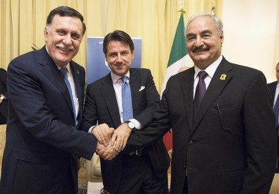 Foto dela stretta di mano tra il generale Haftar e Al Sarraj davanti al premier italiano Conte. Libia