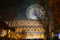 Il Colosseo illuminato di notte e in cielo fuochi d'artificio.