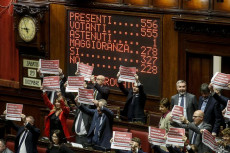 Il tabellone elettronico della Camera con i risultati della votazione mentre i deputati Pd mostrano cartelli di protesta.