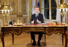 Il Presidente Macron, seduto al tavolo dell'ufficio presidenziale, mentre annuncia la svolta sociale