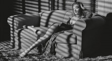 Foto in bianco e nero, una donna seduta in vestaglia sul divano. Calendario Pirelli 2019