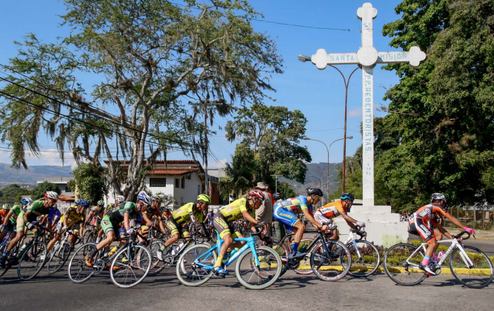 Il gruppo dei ciclisti passano davanti ad una croce. Androni