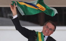 Il neopresidente del Brasile Jair Bolsonaro agita la bandiera nazionale durante l'insediamento.