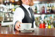 Barista offre una tazza con cappuccino.