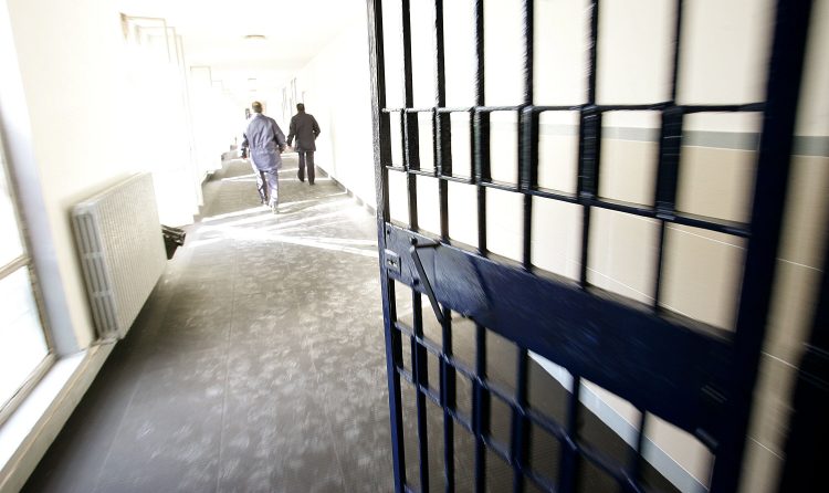Attraverso un cancello del carcere detenuti camminando nel corridoio.