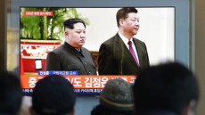 Alcune persone guardano lo schermo tv dove si trasmette l'incontro di Kim con Xi. Corea
