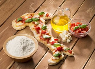 Una pizza a forma d'Italia con olio, pomodoro e basilico.
